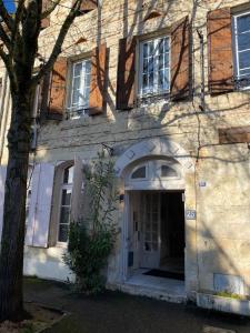 ein Gebäude mit einer weißen Tür und einem Baum in der Unterkunft Relais des Iles chambres d'hôtes in Agen