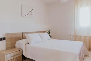 a white bedroom with a white bed and a window at Collbato Resort. in Collbató