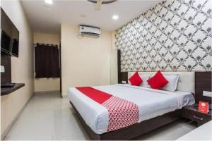 1 dormitorio con 1 cama grande con almohadas rojas en Hotel Aaradhy, en Ujjain
