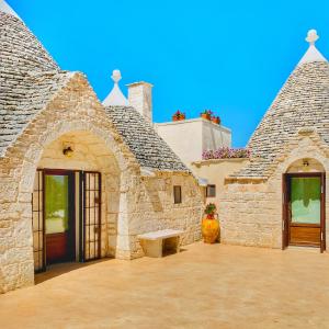 um edifício de pedra com um banco à frente em Trulli Pietra Viva em Alberobello