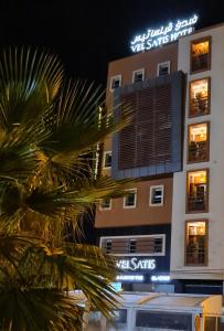 a building with a palm tree in front of it at Hotel VELSATIS in Beni Mellal