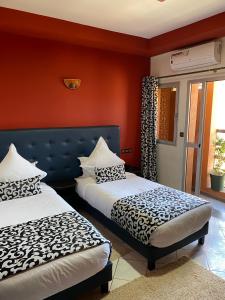twee bedden in een kamer met rode muren bij Hotel VELSATIS in Beni Mellal