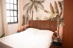 a bedroom with a bed and a palm tree mural at Urca Hotel in Rio de Janeiro