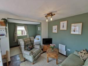 a living room with a couch and a chair at Cosy Coppice Cottage in Whitchurch