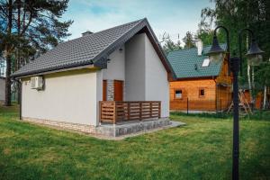 a small white house with a black roof at Domek letniskowy SZWED-POL in Kujan