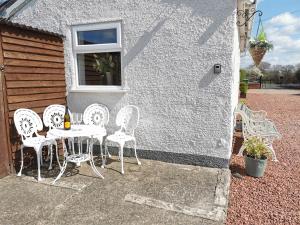 una mesa y sillas sentadas fuera de una casa en Cosy Coppice Cottage en Whitchurch