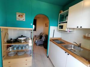 a kitchen with white cabinets and a green wall at Da Ale in Dormelletto