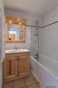 uma casa de banho com um lavatório, uma banheira e um espelho. em Résidence Goélia Les Flocons d'Argent em Aussois