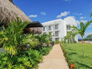 a white building with palm trees and a sidewalk at Hotel Arbóreo Doradal in Doradal