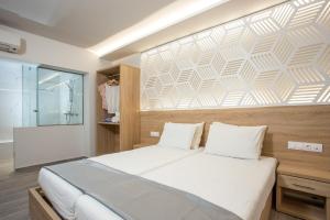 a bedroom with a large white bed with a wall at Tsampika Hotel Faliraki in Faliraki