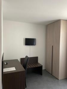 a room with a desk and a cabinet with a tv on the wall at Hotel della Stazione in Maroggia