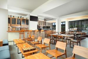 北干巴鲁BATIQA Hotel Pekanbaru的有木桌椅和酒吧的餐厅