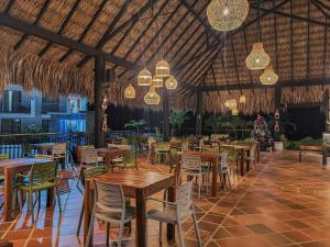 a restaurant with wooden tables and chairs and chandeliers at Hotel Arbóreo Doradal in Doradal