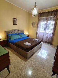 a bedroom with a large bed and a chandelier at Appartamento Fiore Roma Cinecittà in Rome