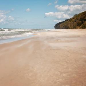 a sandy beach with the ocean in the background at Balfala - komfortowe parterowe domki nad morzem z klimatyzacją in Ostrowo