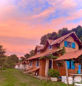 a row of houses with a sunset in the background at Pousada Shangrilá São Thomé in São Thomé das Letras