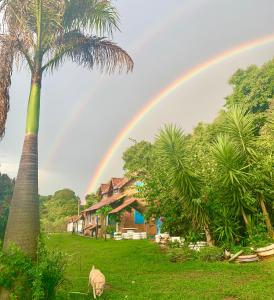 um arco-íris sobre uma casa com uma palmeira em Pousada Shangrilá São Thomé em São Thomé das Letras