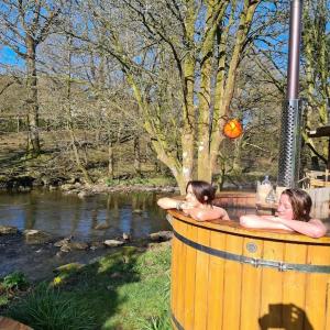 two women in a hot tub next to a river at Bohemian suite on Rydal Water. Beautiful location! in Rydal