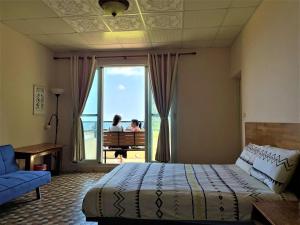 Un dormitorio con una cama y una ventana con 2 personas en Shiacare Hostel, en Isla Verde
