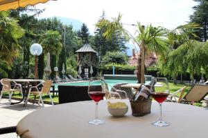twee glazen wijn op een tafel naast een zwembad bij Garni Weingut in Merano