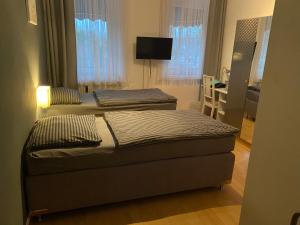 two beds in a room with a desk and a television at Pension Pagalies in Düsseldorf