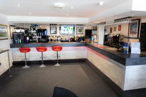 a bar with red stools in a restaurant at Dudsbury Golf Club - Hotel And Spa in Ferndown