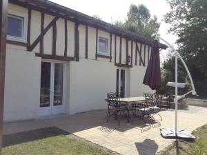 un patio con mesa, sillas y sombrilla en Le Nichoir Lac du Der, en Droyes