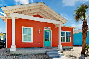 a orange house with a blue door and a palm tree at Coral Cove in Port Aransas