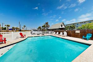 a swimming pool with chairs and a fence at Coral Cove in Port Aransas