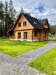una casa de madera con techo negro en un camino de piedra en Całoroczne domy z bala - CASA DEL CZYŻYK, en Serwy