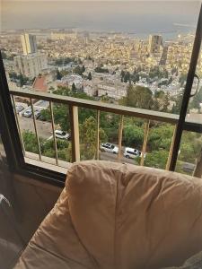 a couch in a room with a view of a city at Panorama Bay View 3 room in Haifa