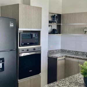 a kitchen with a stove and a refrigerator at Apartamento en Sector Ciudad Jardin Barranquilla cerca al Centro Comercial Unico in Barranquilla