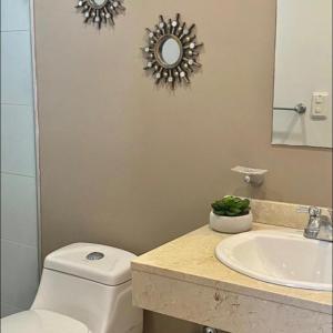 a bathroom with a toilet and a sink and a mirror at Apartamento en Sector Ciudad Jardin Barranquilla cerca al Centro Comercial Unico in Barranquilla