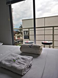 a bed with towels on it with a large window at aparta hotel turístico a 2 km parque del café in Montenegro