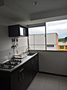 a kitchen with a stove top oven next to a window at aparta hotel turístico a 2 km parque del café in Montenegro