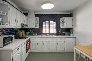 a white kitchen with white cabinets and a window at Vila com piscina e jardim privado in Altura
