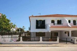 une maison blanche avec une clôture devant elle dans l'établissement Vila com piscina e jardim privado, à Altura