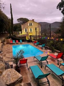 a swimming pool with chairs and a house in the background at Les Horizons - SPA-JACUZZI - MASSAGE- SAUNA - 4 SAISONS - Piscine chauffée Toute l'année - 800m centre ville Nyons in Nyons