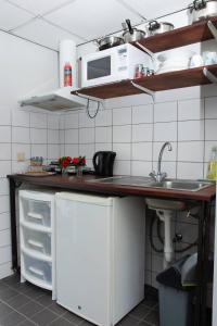 eine Küche mit einer Spüle und einer Mikrowelle in der Unterkunft Boom Apartments in Paramaribo