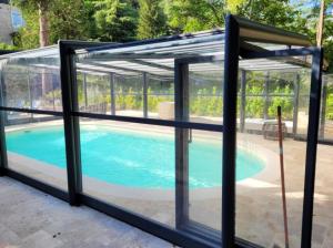 a pool house with a glass enclosure and a swimming pool at Villa confortable à Carlux avec piscine privée et jardin in Carlux
