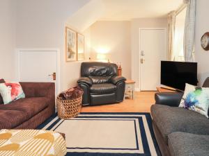 een woonkamer met lederen meubels en een flatscreen-tv bij Coach House Cottage in Carnforth