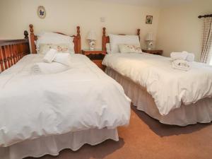 2 bedden in een slaapkamer met witte lakens bij Coach House Cottage in Carnforth