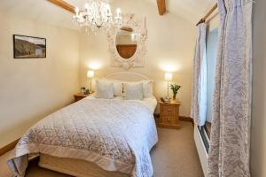 Un dormitorio con una cama blanca y un espejo. en Finest Retreats - Bretherdale Hall, en Tebay