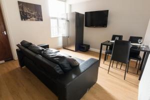a living room with a black leather couch and a table at Modern and Spacious House Perfect for Teams in Luton