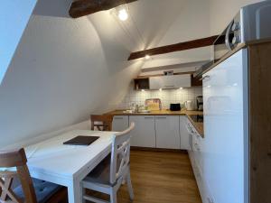 a kitchen with a white table and a white refrigerator at Urlaub im Fachwerk - Das Sattlerhaus in Quedlinburg