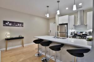 a kitchen with a white counter and bar stools at *New* XquisiteMidCenturyM0d~ Condo *OTR* w/Parking in Cincinnati