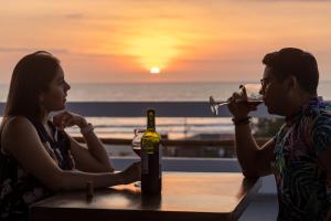 un hombre y una mujer sentados en una mesa bebiendo vino en Hotel Sol y Playa Montañita en Montañita