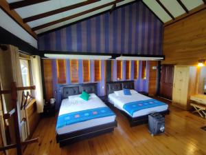 two beds in a room with wooden walls and wooden floors at Amansara Bungalow in Nuwara Eliya