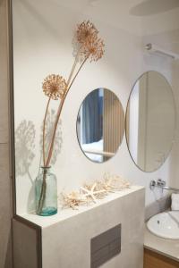 a bathroom with two mirrors and a vase with flowers at Aparthotel Park - By The Sea in Gdynia