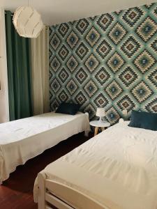1 dormitorio con 2 camas y pared con papel pintado en El Mayul 2' centre, plage, WiFi, au calme, clim, parking,, en Collioure
